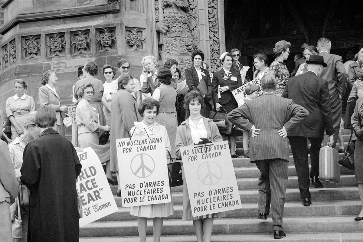 Duncan Cameron, <i>Women on steps holding signs “No Nuclear Arms for Canada / Pas d’armes nucléaires pour le Canada,”</i> Montreal, 1961. Library and Archives Canada, PA-209888