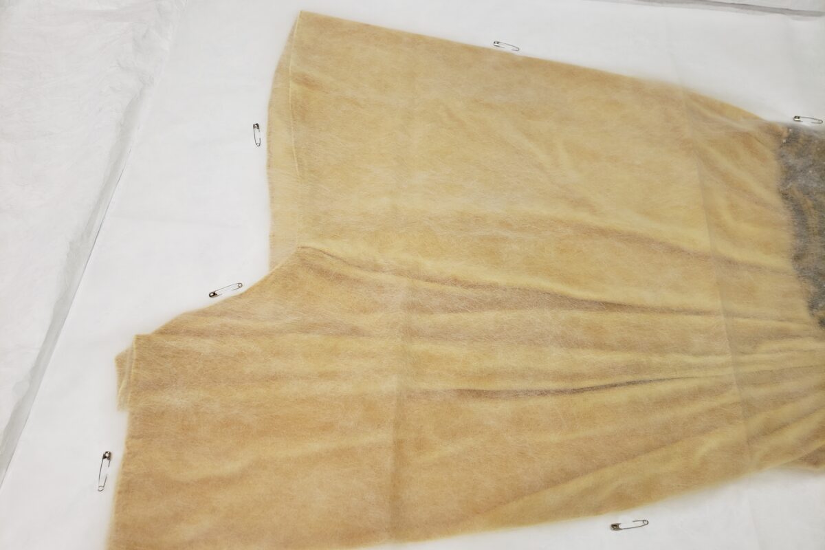 Vue de la jupe de la robe de soirée sur son enveloppe, recouverte d’un Cerex épinglé au Tyvek du support.